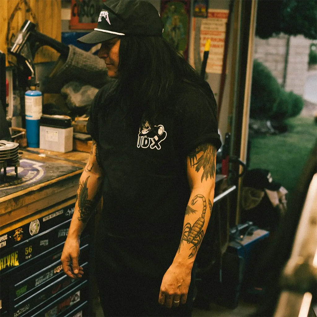 Person wearing a black t-shirt with a logo in a garage setting