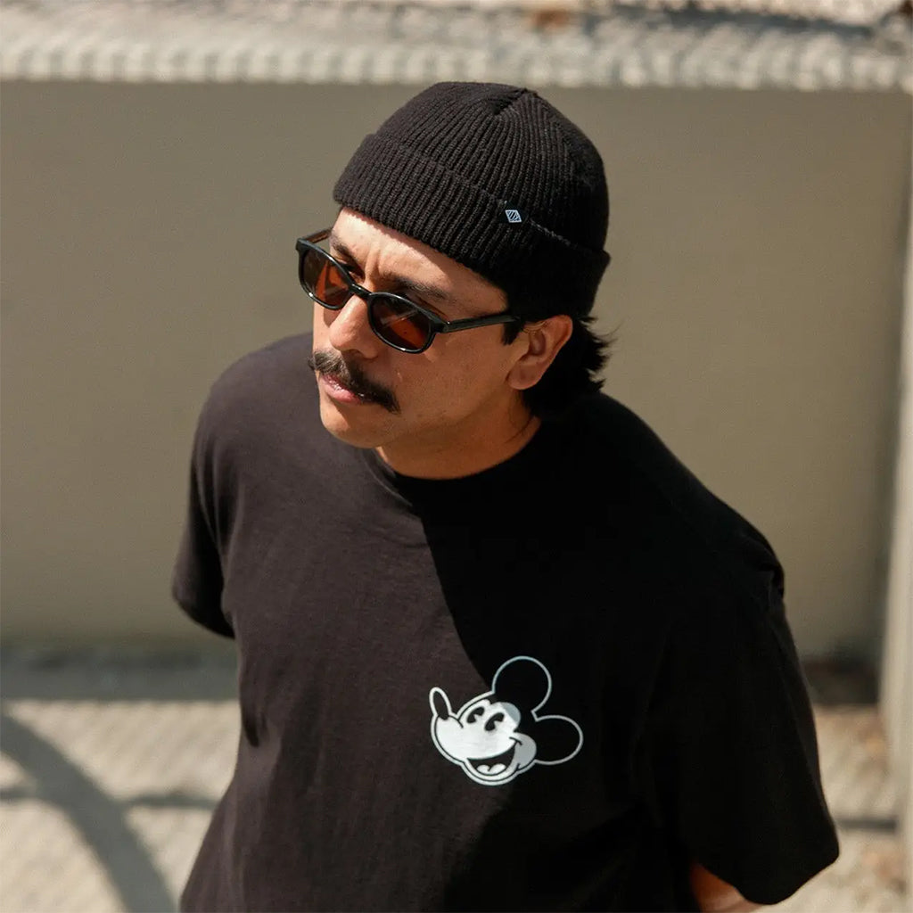Man wearing a black beanie and sunglasses, with a black t-shirt featuring a white graphic design.