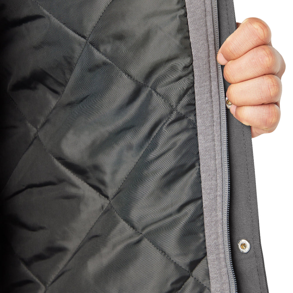 Close-up of a hand holding the zipper of a quilted jacket.