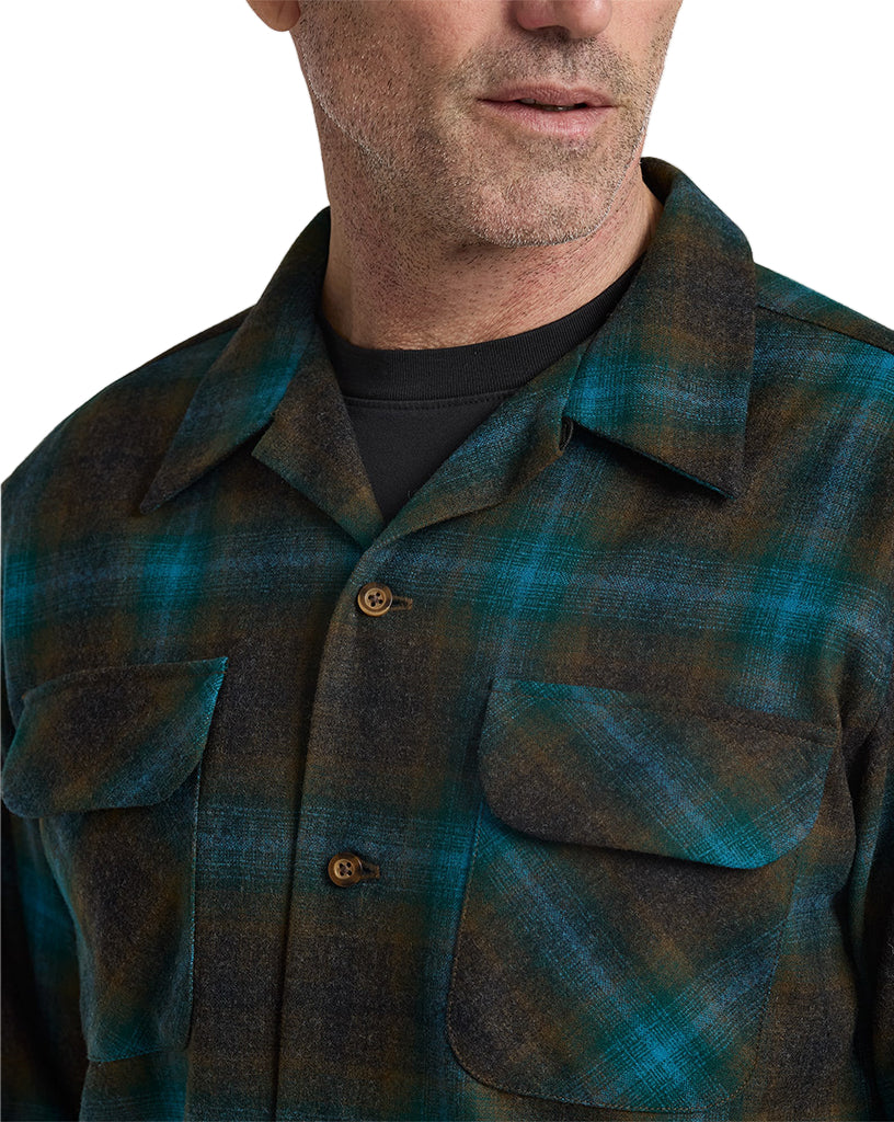 Man wearing a green and brown plaid shirt against a neutral background