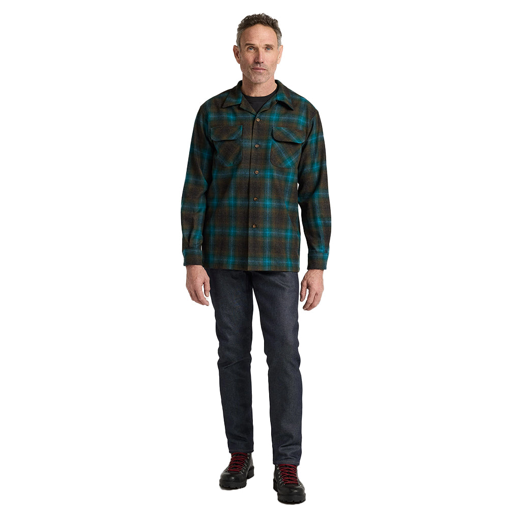 Man wearing a plaid shirt and dark jeans on a white background