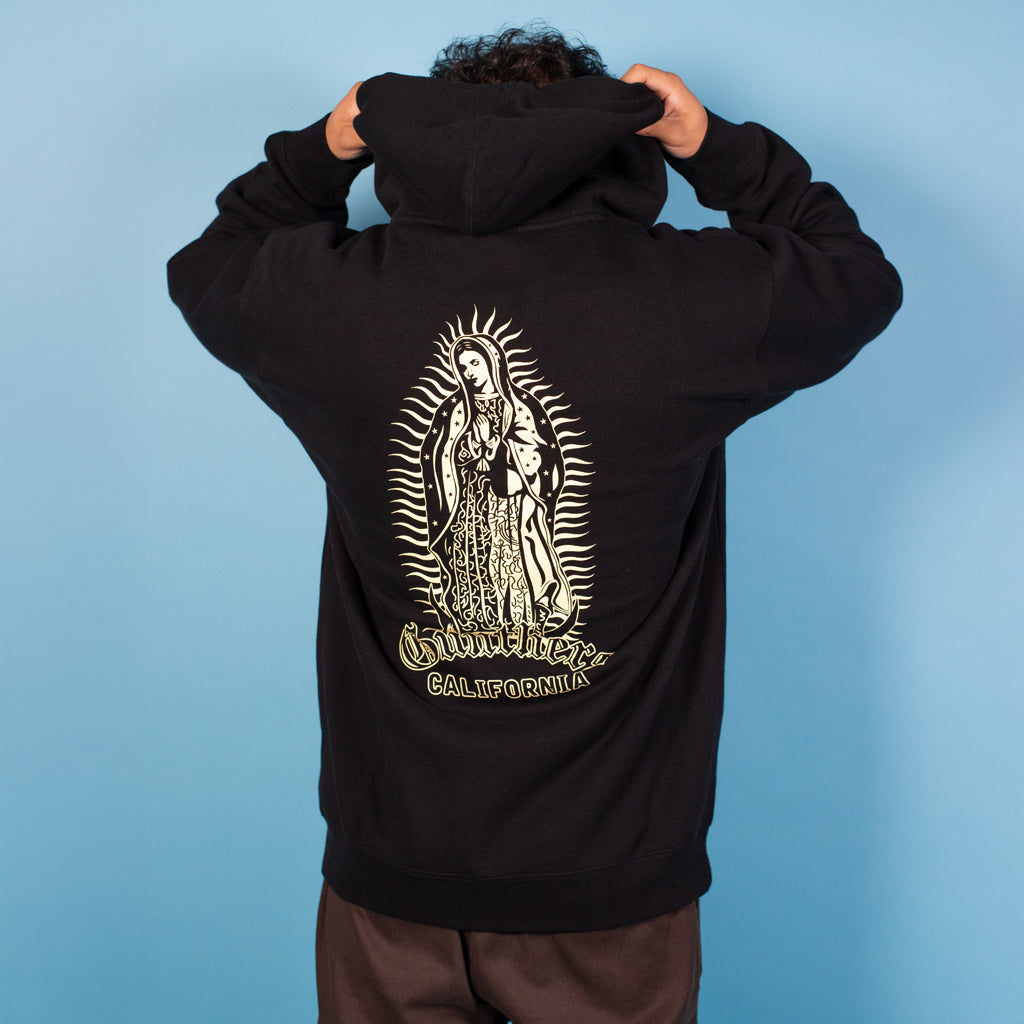 Person wearing a black hoodie with a religious icon design on the back against a blue background