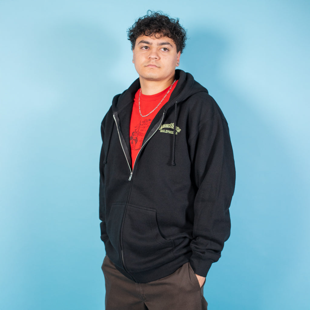 Person wearing a black hoodie with a red shirt underneath on a blue background