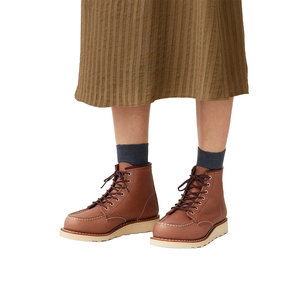 Brown leather boots worn with a brown skirt and dark socks on a white background