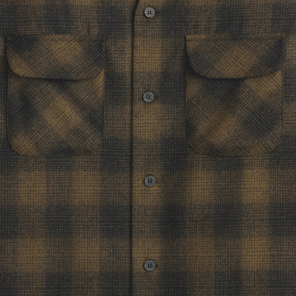 Close-up of a brown and black plaid shirt with button details.