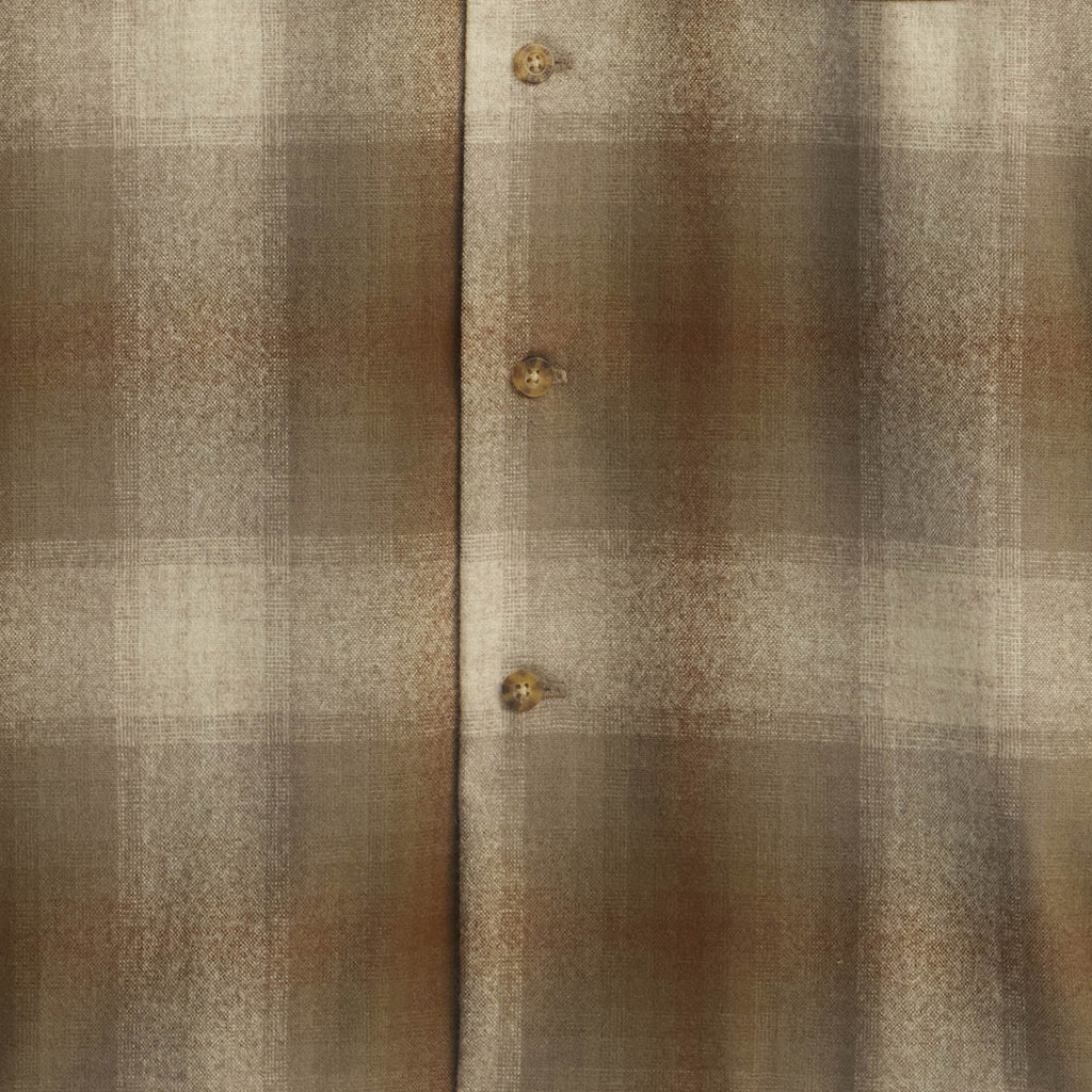 Close-up of a textured fabric with plaid pattern and buttons.