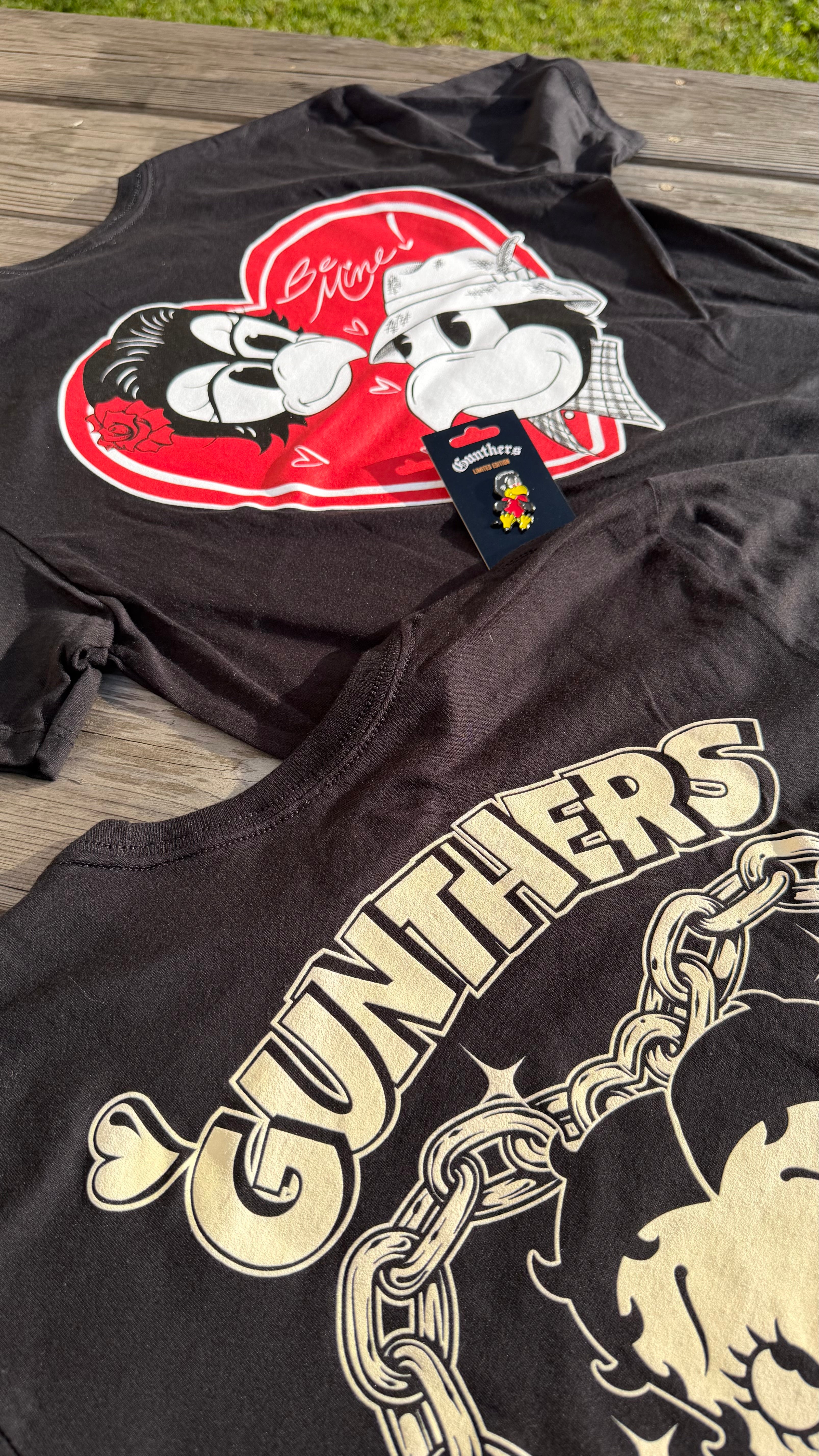 Black t-shirt with graphic design and brand tag on a wooden surface