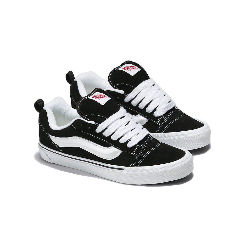 A pair of Vans Knu Skool sneakers with black suede uppers, a puffed up white tongue, white laces, and a black and white checkered pattern on the side stripe.