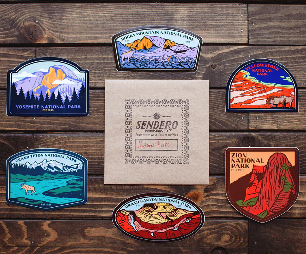 National park stickers on a wooden surface with a Sendero paper product.