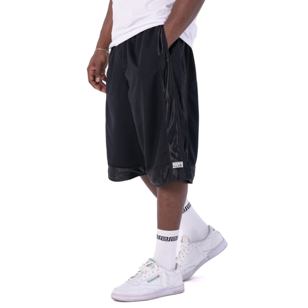 Person wearing black shorts, white socks, and white sneakers on a white background