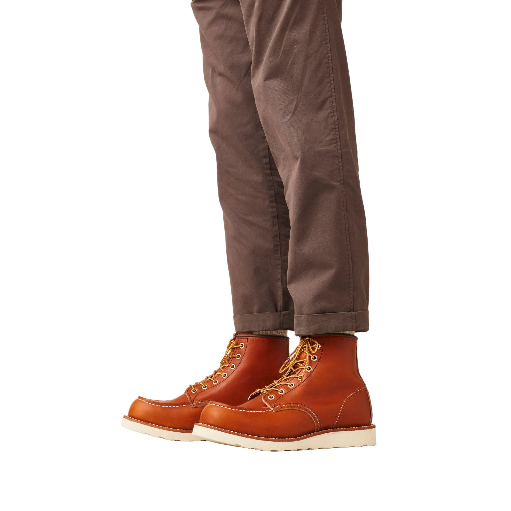 Brown leather boots with beige soles worn with brown pants on a white background