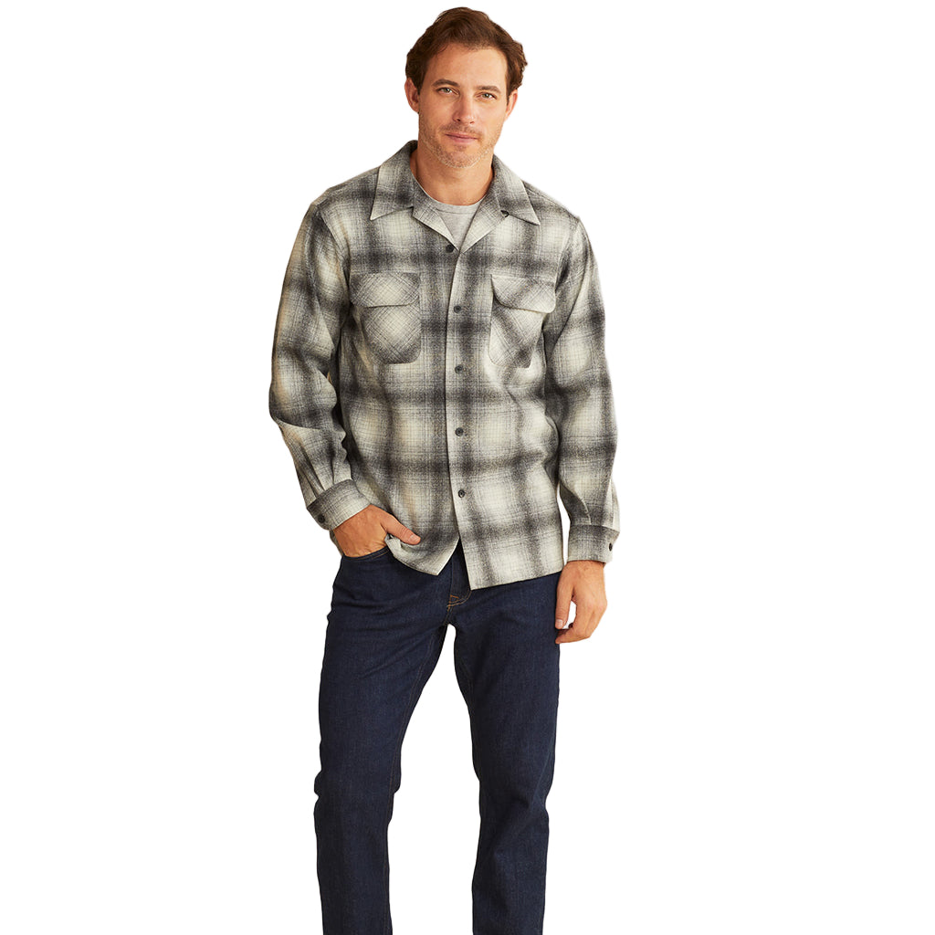 A male model wearing a long-sleeved, grey plaid wool shirt with two front pockets, standing against a neutral background.