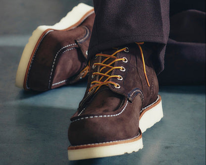 Brown leather boots with white soles on a dark surface