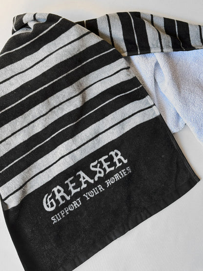 Black and white striped towel with 'Greaser Support Your Hobbies' text on a light background