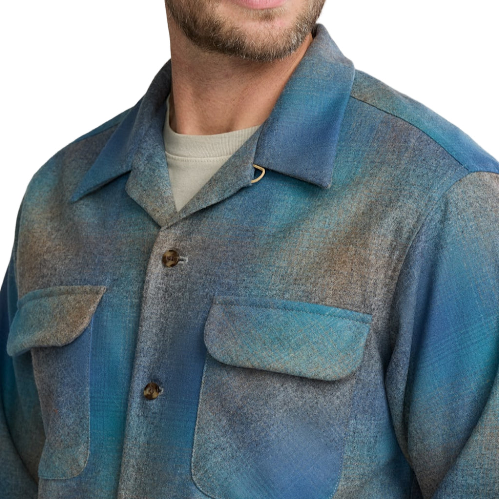 Man wearing a blue plaid shirt against a neutral background