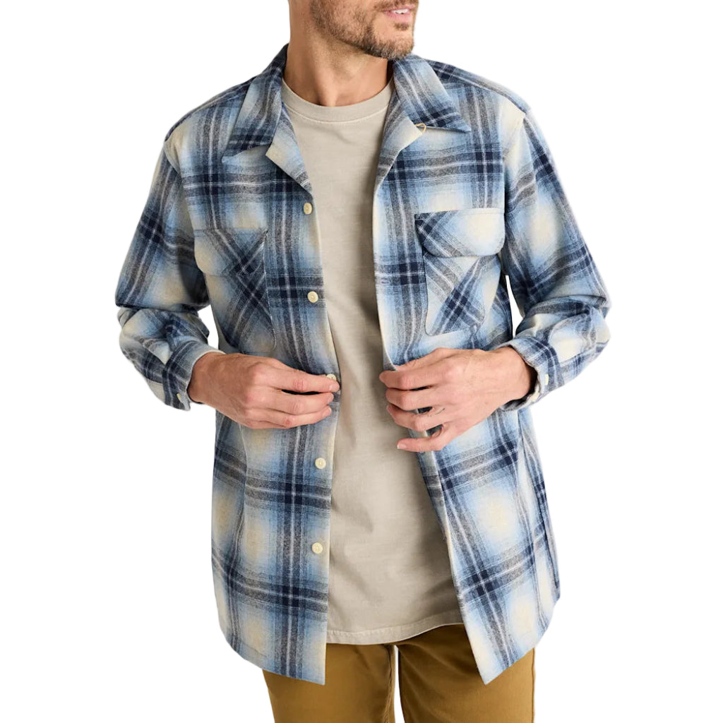 Man wearing a blue plaid shirt over a gray t-shirt on a white background