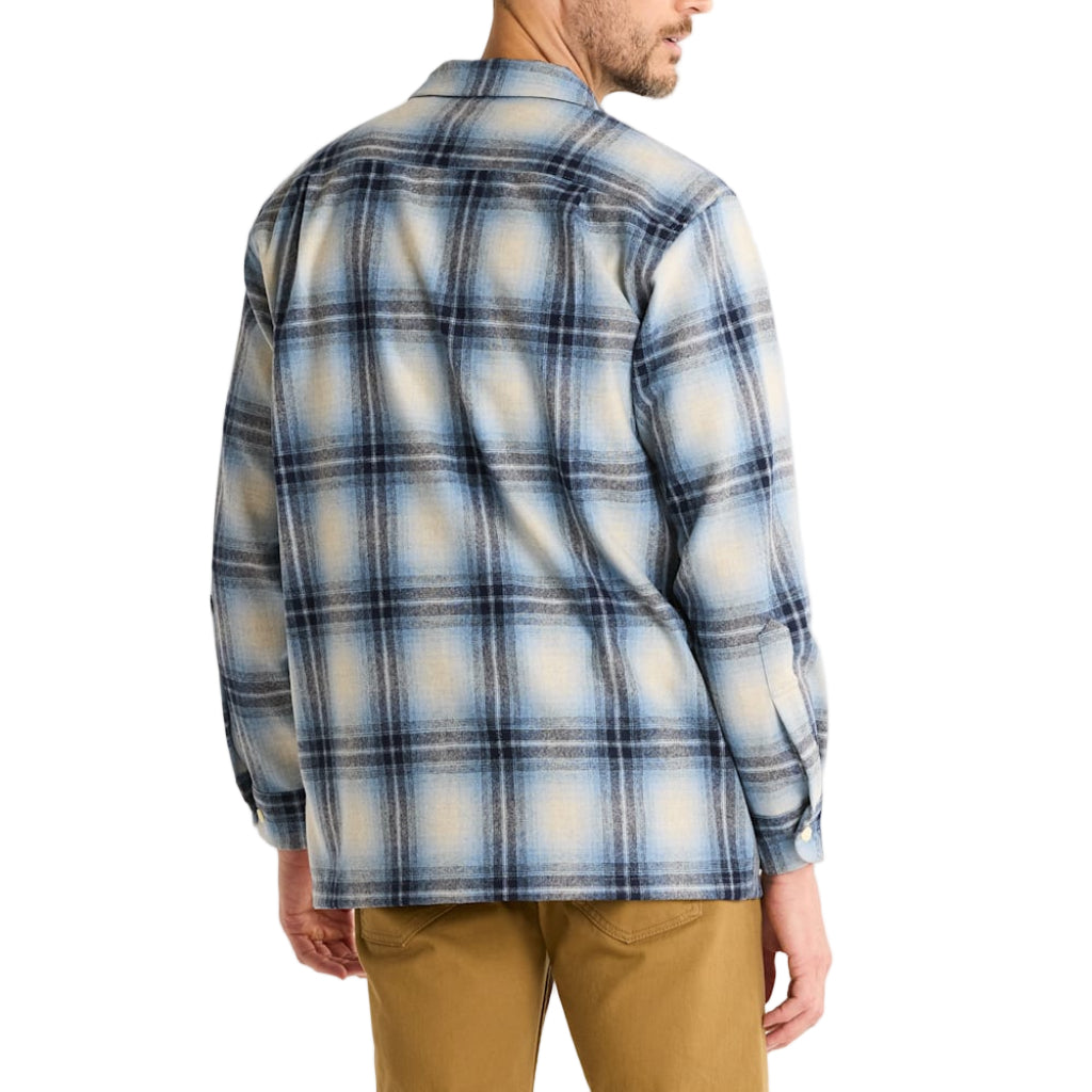 Man wearing a blue and white plaid shirt on a plain background