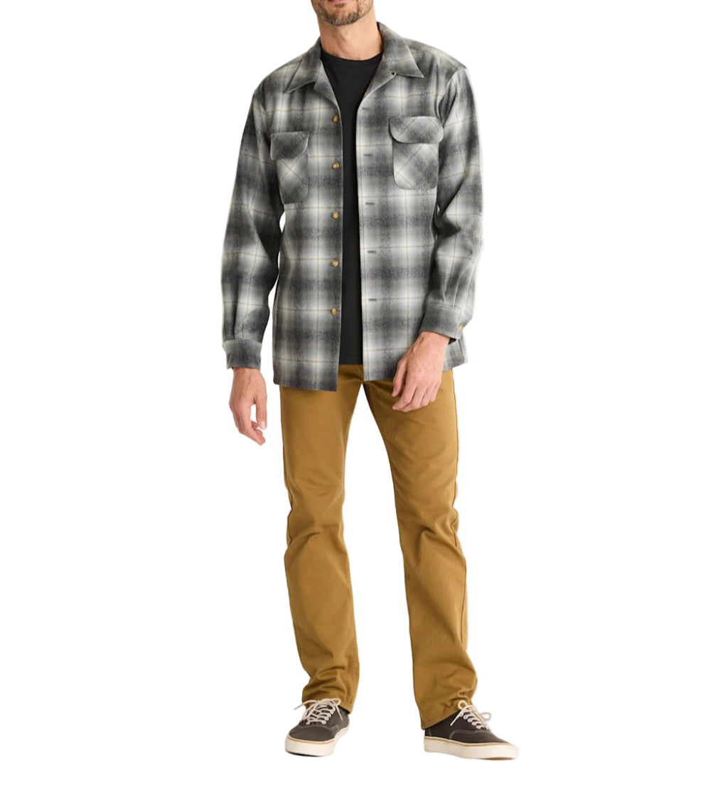 Man wearing a plaid shirt and brown pants on a white background
