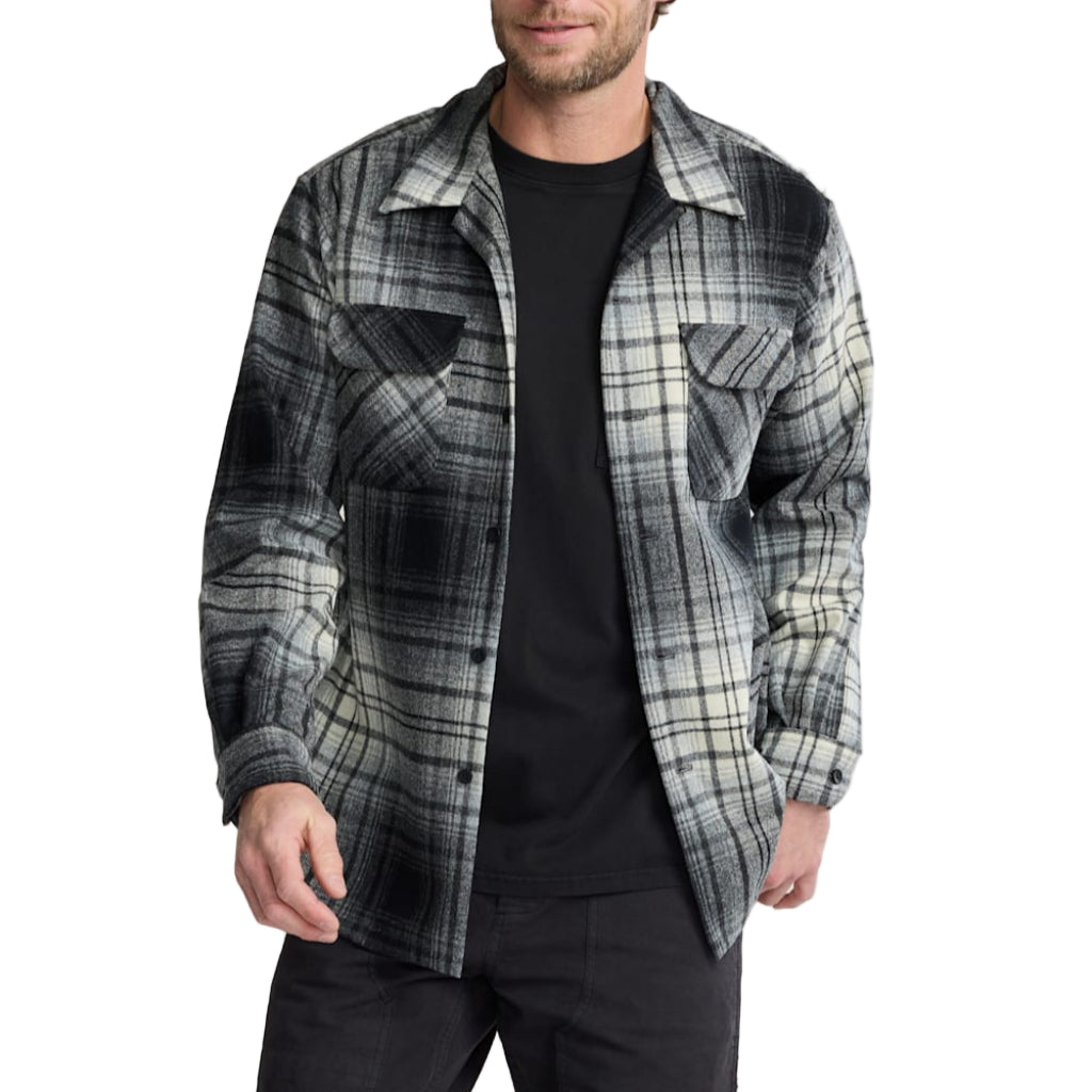 Man wearing a plaid shirt over a black t-shirt on a plain background