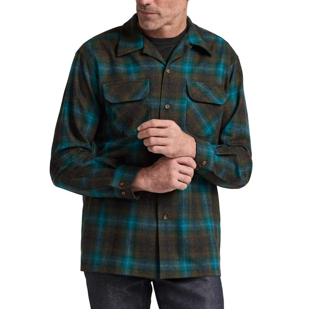 Man wearing a green and brown plaid shirt against a plain background
