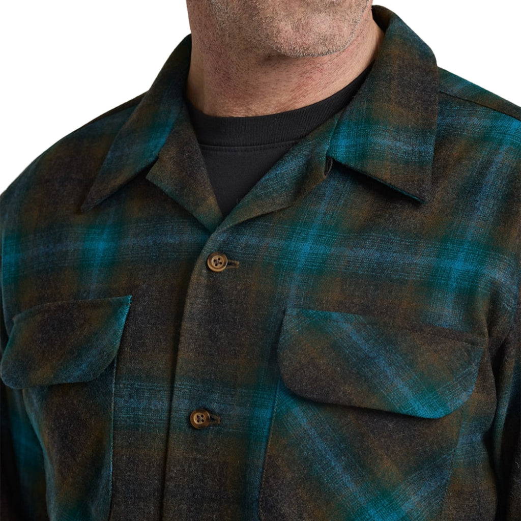 Close-up of a person wearing a green and blue plaid shirt with a plain white background