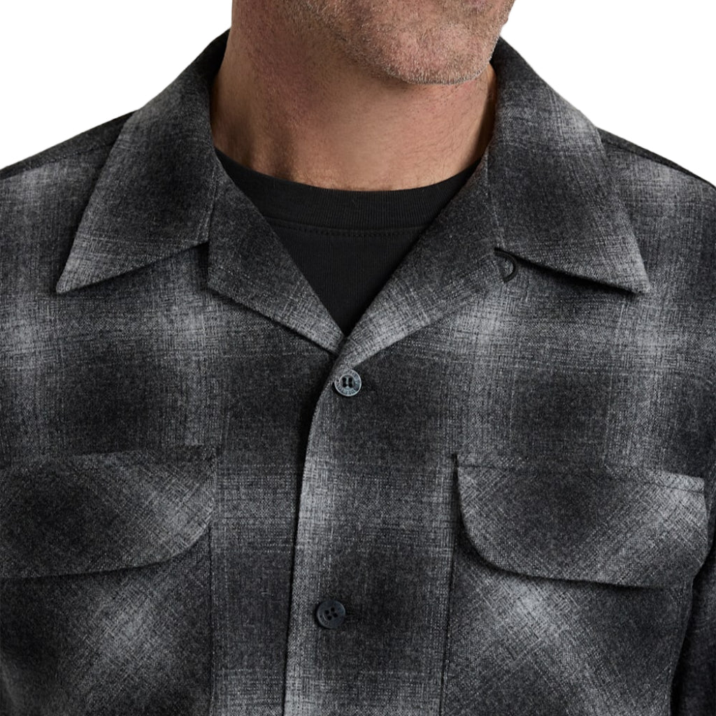 Close-up of a person wearing a gray checkered shirt against a white background