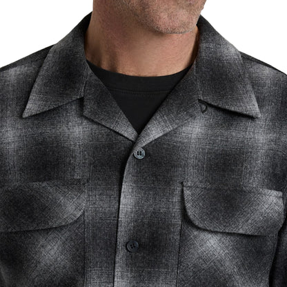Close-up of a person wearing a gray checkered shirt against a white background