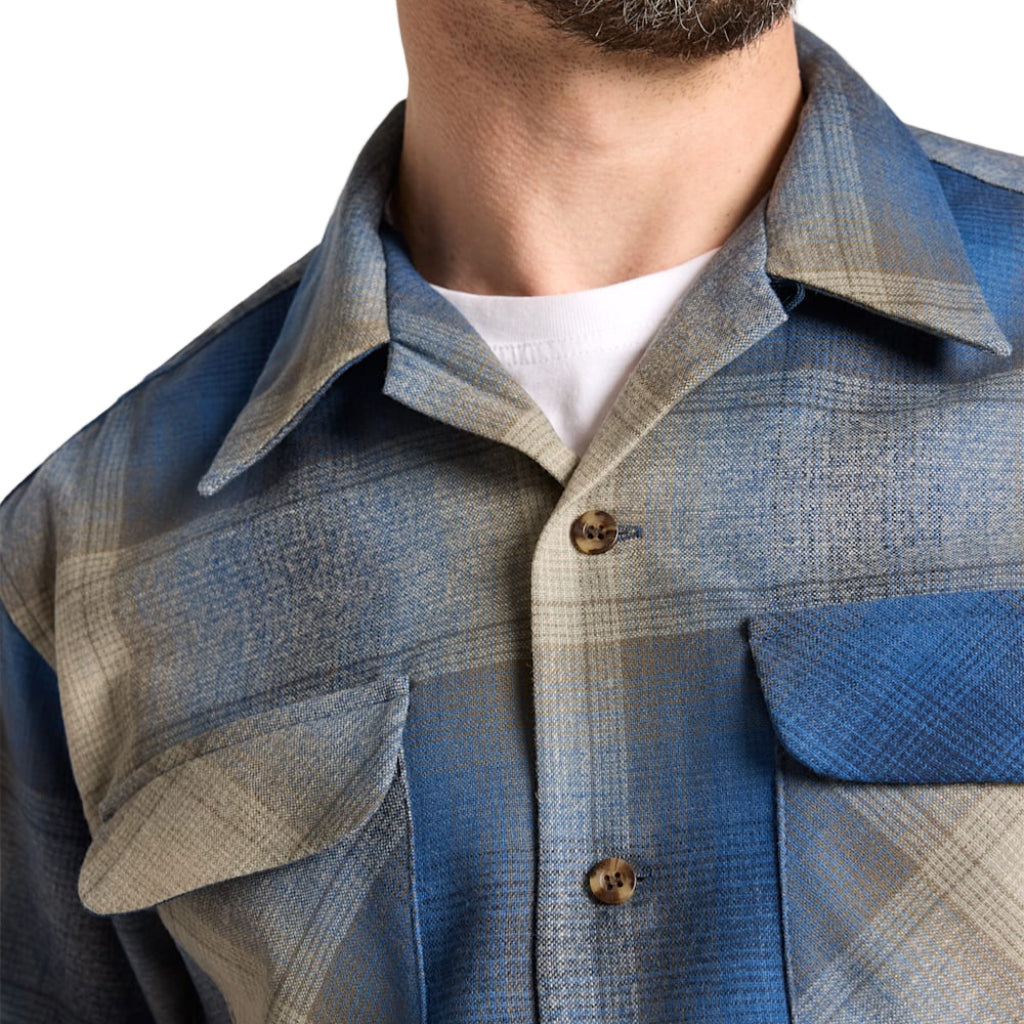 Close-up of a person wearing a blue and gray plaid shirt with a white collar.