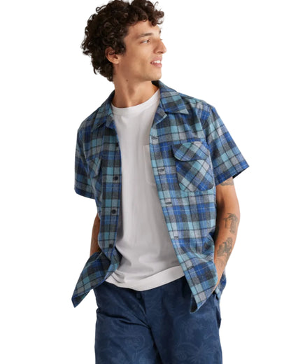 Man wearing a blue plaid shirt over a white t-shirt on a white background