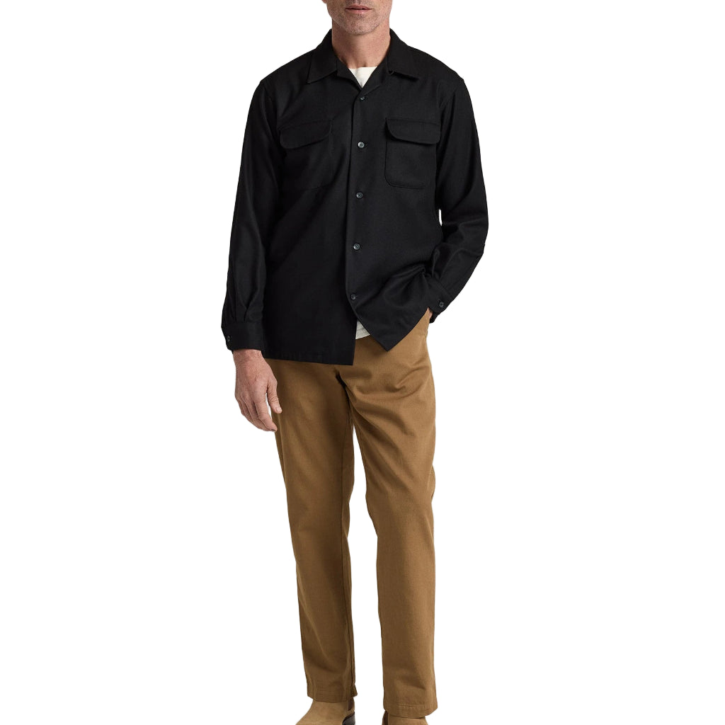 Man wearing a black shirt and brown pants on a white background