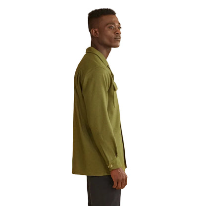 Man wearing a green shirt and dark pants on a white background