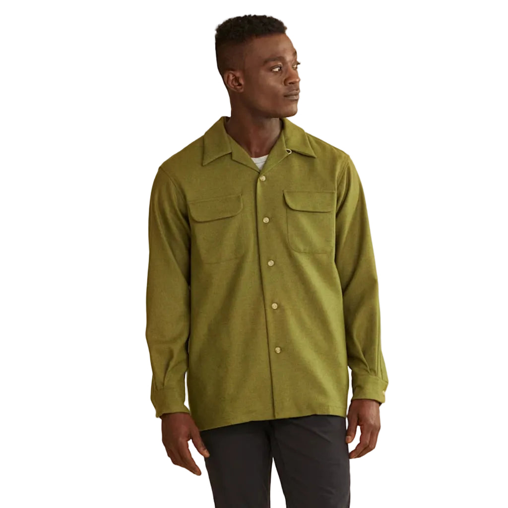 Man wearing a green shirt and dark pants on a white background
