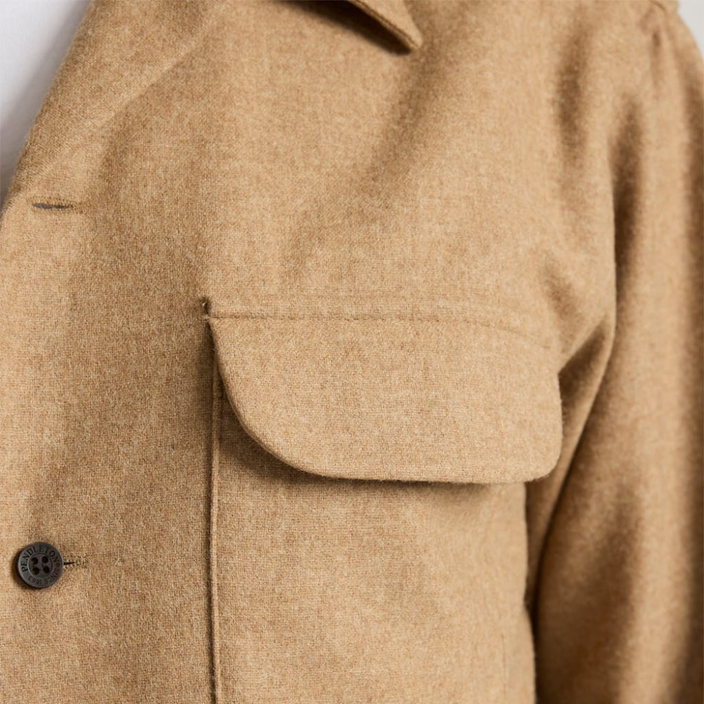 Close-up of a beige coat with a pocket and button detail.