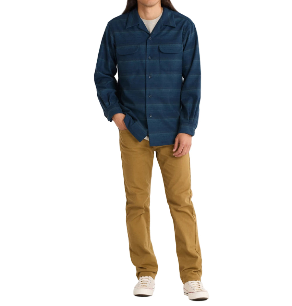 Man wearing a blue plaid shirt and tan pants on a white background