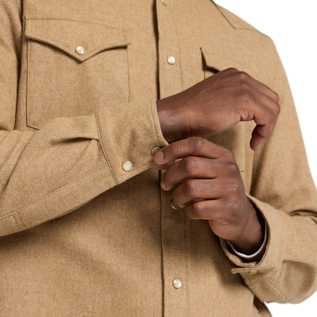 Close-up of a person wearing a beige jacket with a hand adjusting the sleeve.