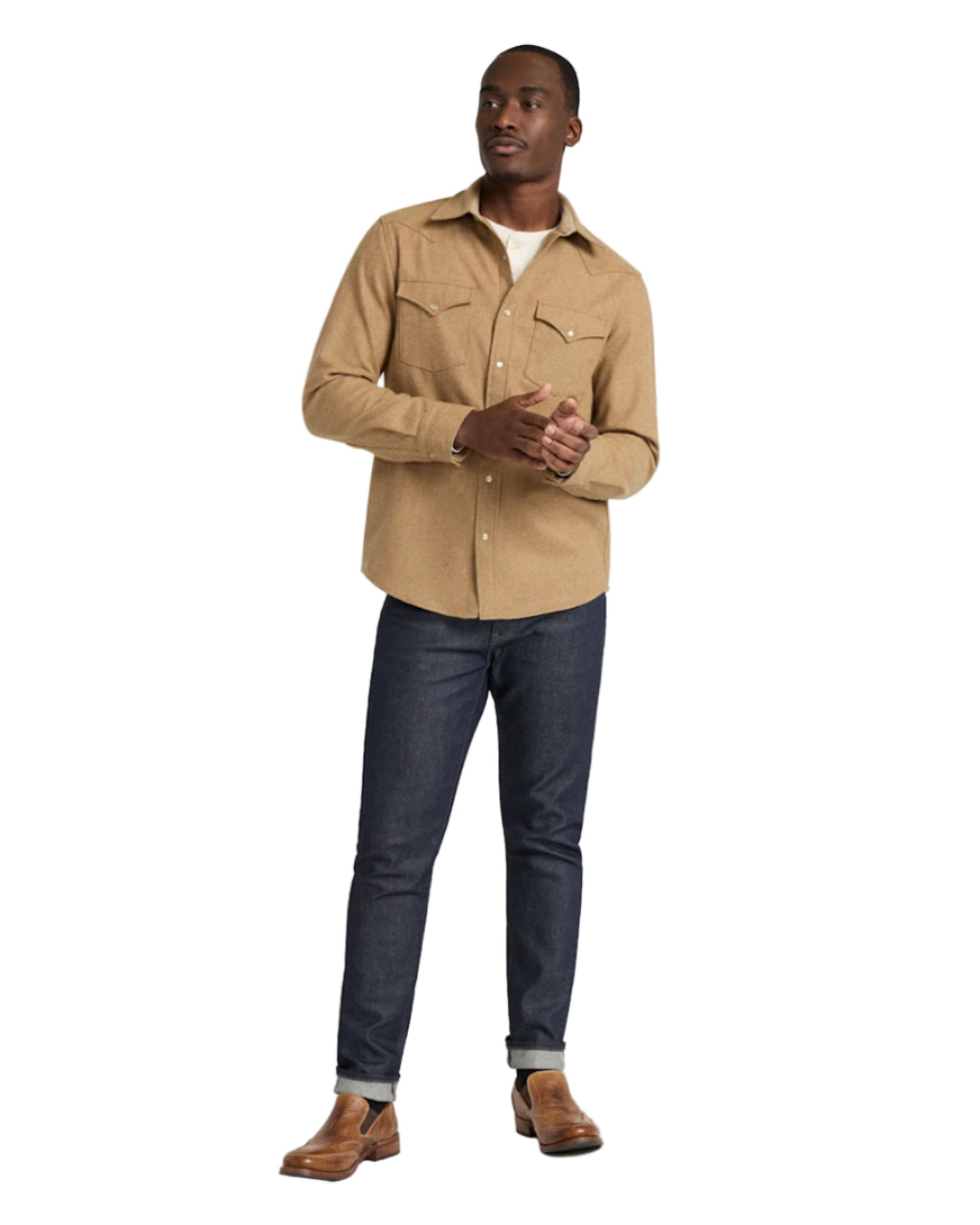 Man wearing a beige shirt and dark jeans on a white background