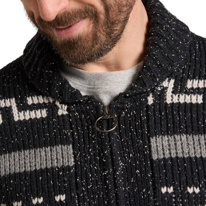 Close-up of a person wearing a black and gray patterned jacket with a zipper.