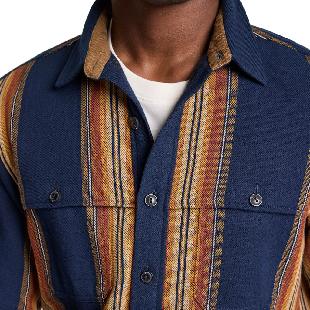 Close-up of a person wearing a blue shirt with striped sleeves and collar.
