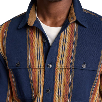 Close-up of a person wearing a blue shirt with striped sleeves and collar.