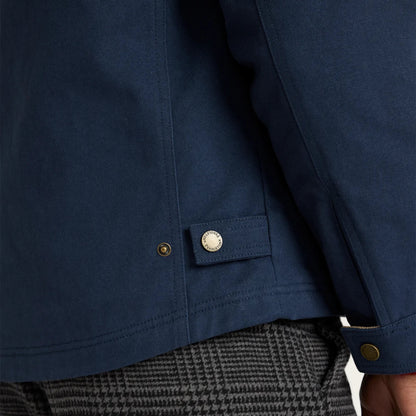 Close-up of a blue jacket with a button and a person wearing gray pants.