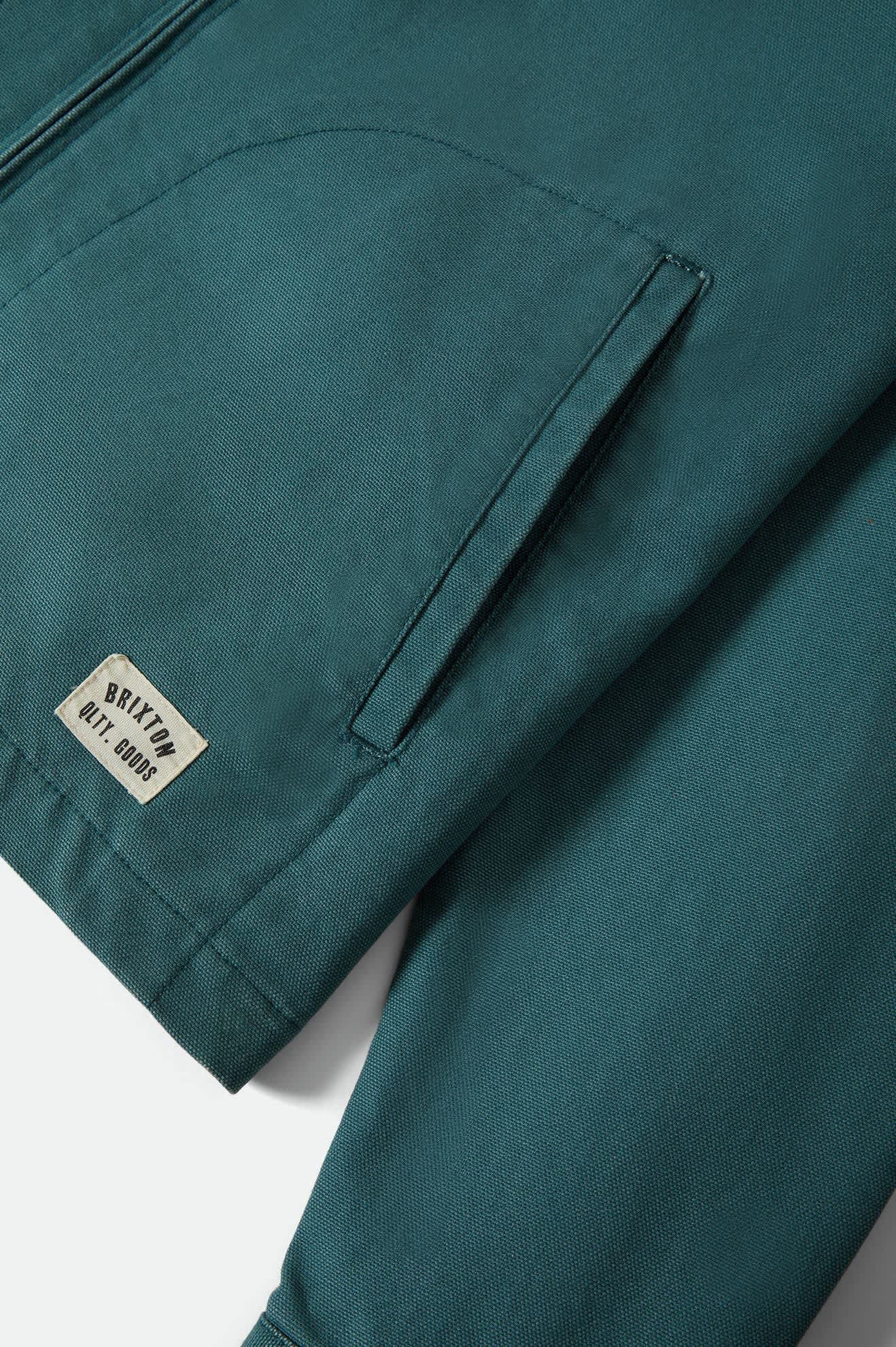 Teal jacket with a brand label on a white background