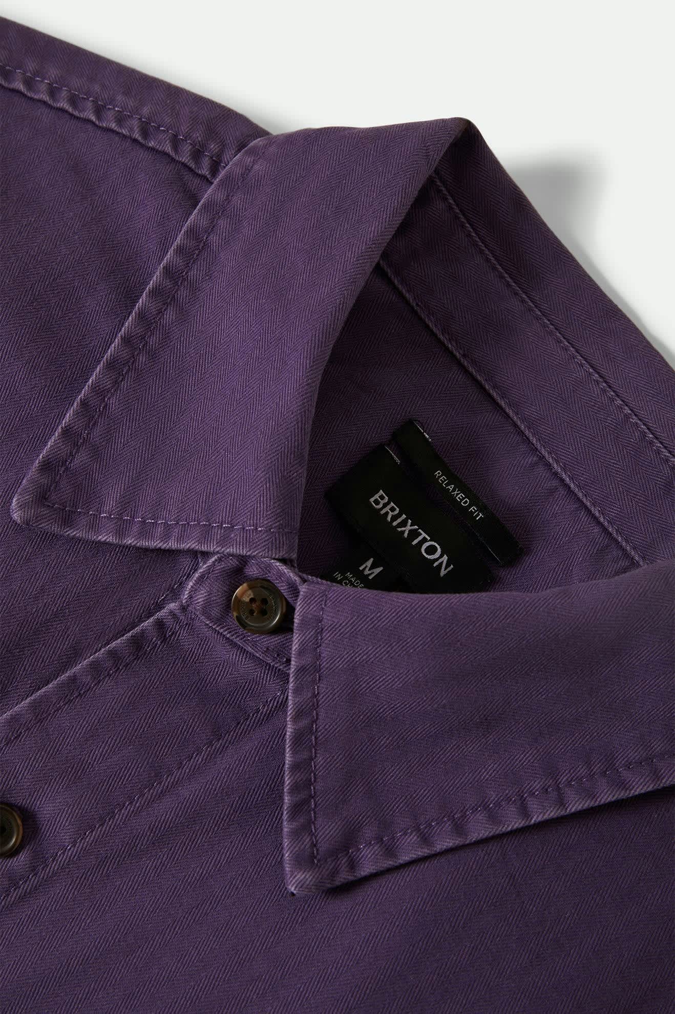 Close-up of a purple shirt with a Brixton tag on a white background