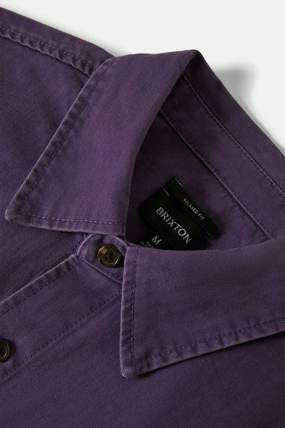 Close-up of a purple shirt with a Brixton tag on a white background