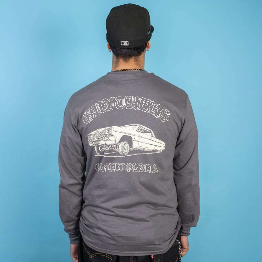 Person wearing a gray long-sleeve shirt with a graphic design on the back against a blue background