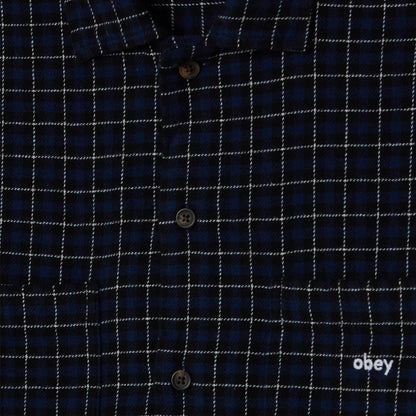 Close-up of a blue checkered shirt with 'obey' logo