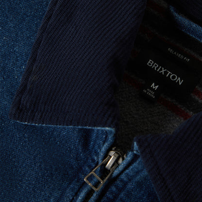 Close-up of a navy jacket with a Brixton label on a blue background