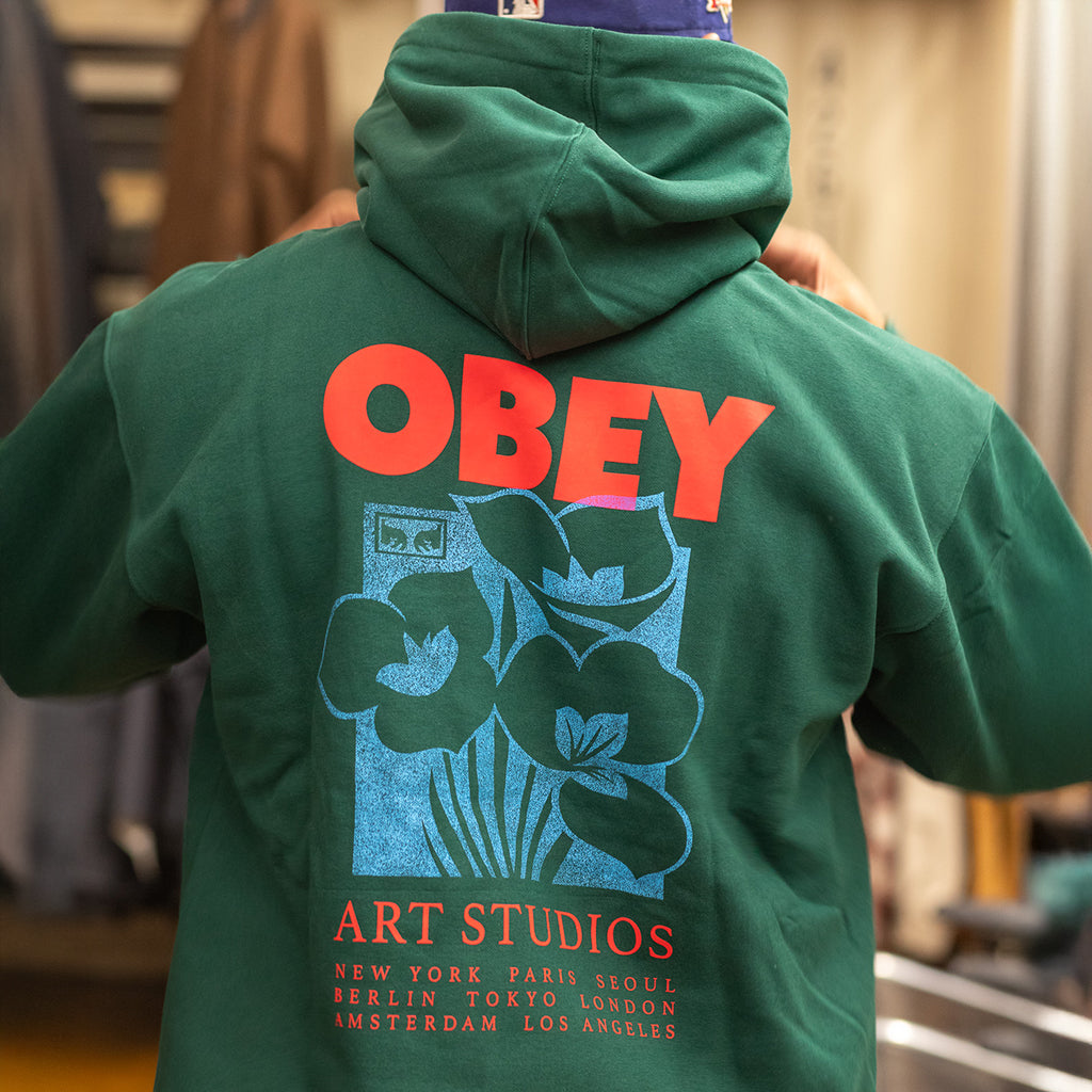 Green hoodie with 'OBEY' logo and text on the back, worn by a person.