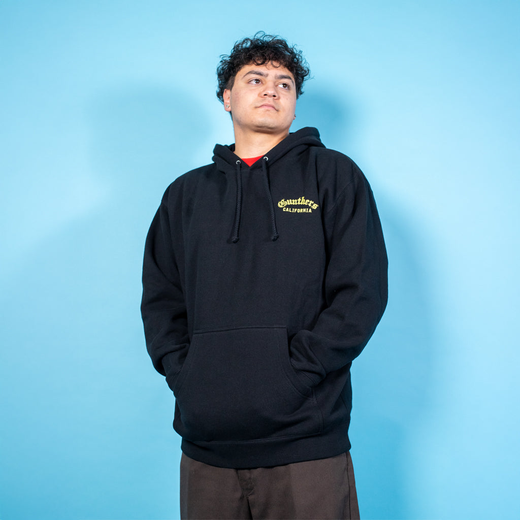 Person wearing a black hoodie with a logo on a blue background