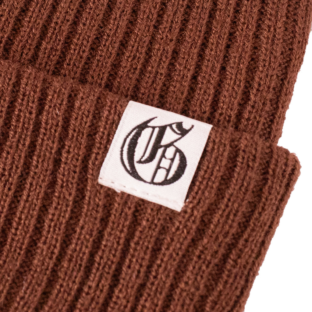 Brown knit beanie with a logo tag on a white background