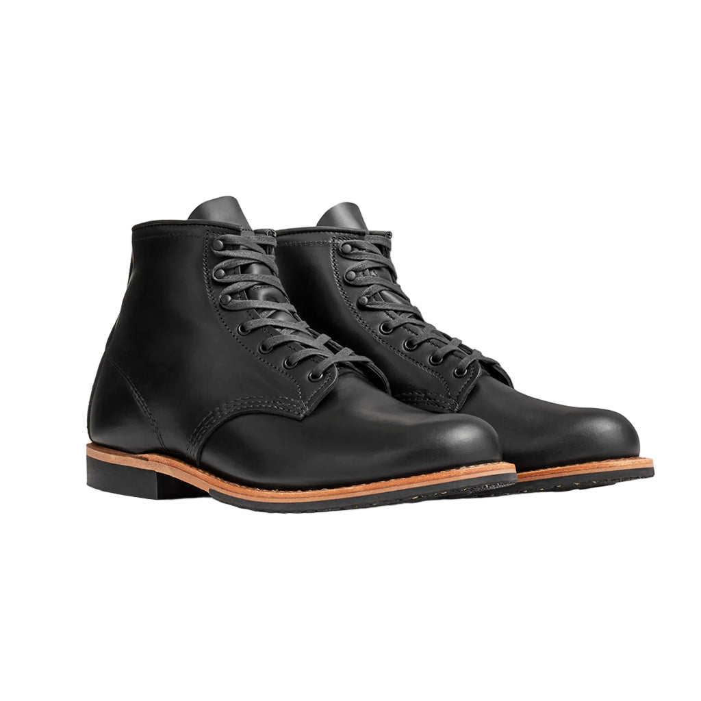 Pair of black leather boots with brown soles on a light gray background